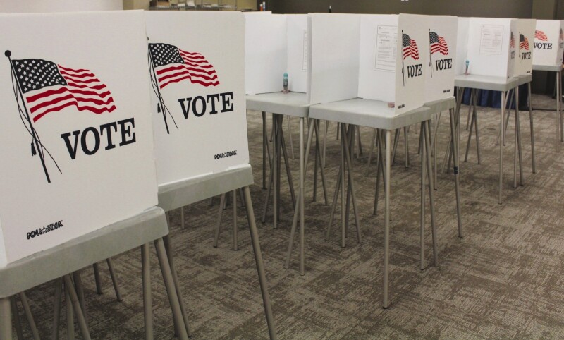 Multiple voting booths the color white labeled with the American Flag