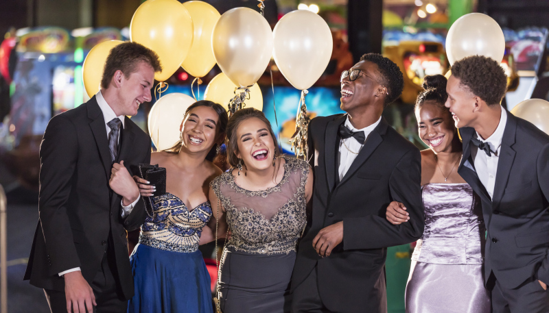 group of teenagers laughing while in prom attire.