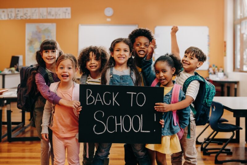 a group of smiling children holding a sign that says back to school